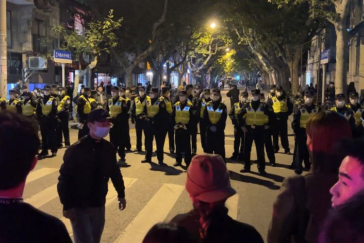 Polisi China menutup akses jalan ke lokasi demo di Shanghai pada Minggu (27/11/2022). Warga China memprotes pembatasan ketat dalam kebijakan nol Covid China di Shanghai dan Beijing sejak siang hari itu.