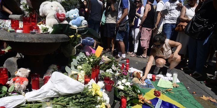 Seorang wanita meletakkan sesuatu di dekat karangan bunga, pesan-pesan, dan sejumlah mainan anak yang dipasang untuk mengenang serangan di Kota Cambrils, Spanyol pada Jumat (18/8/2017).  