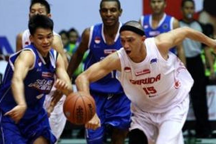 Pemain Garuda Kukar Bandung, Vinton Nolland Surawi (tengah, jersey putih) melewati pemain Satria Muda BritAma, pada pertandingan National Basketball League (NBL) 2012-2013.