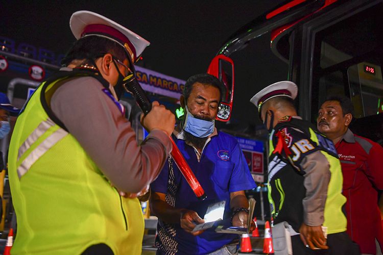 Petugas kepolisian memeriksa dokumen milik calon pemudik yang terjaring razia penyekatan di Pintu Tol Cikarang Barat, Bekasi, Jawa Barat, Kamis (21/5/2020). Calon pemudik yang terjaring razia penyekatan oleh Polda Metro Jaya tersebut dibawa ke Terminal Pulo Gebang untuk kemudian diarahkan kembali menuju Jakarta.