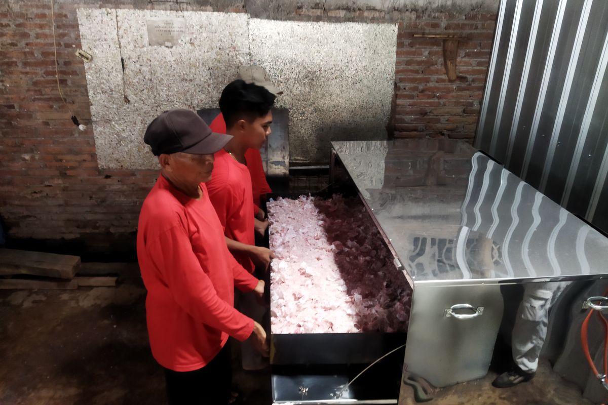 Para pekerja memasukkan cacahan botol Yakult bekas ke dalam mesin oven di CV Bina Usaha Mandiri di Nogosari, Boyolali, Kamis (7/3/2024).