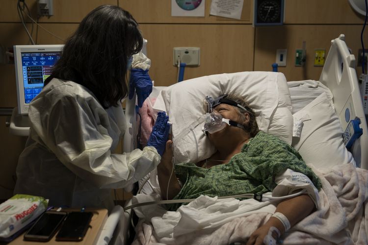 Becky Gonzalez (kiri) dan kawan lamanya, Mary Lou Samora (71) yang merupakan pasien Covid-19, saling menggenggam tangan dan menyemangati di Providence Holy Cross Medical Center, Los Angeles, Amerika Serikat, Jumat (17/12/2021).