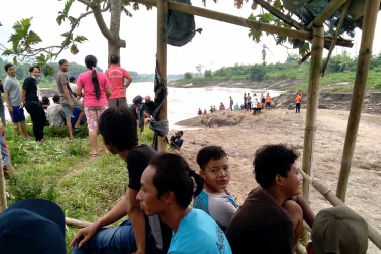 Puluhan warga petugas kepolisian dan BPBD berkumpul di sekitar lokasi terjatuhnya Bagas ke aliran Sungai Brantas di Desa Mronjo, Kecamatan Selopuro, Kabupaten Blitar, Rabu (23/3/2022)