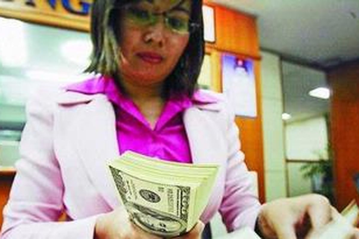 Staf penukaran valuta asing di kawasan Kwitang, Jakarta, memeriksa lembaran dollar Amerika Serikat.