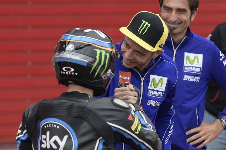 Pebalap Movistar Yamaha MotoGP asal Italia, Valentino Rossi, memberikan selamat kepada pebalap Moto3 dari Sky Racing Team VR46, Andrea Migno (Italia), yang finis di urutan kelima pada balapan GP Argentina di Autodromo Termas de Rio Hondo, Minggu (9/4/2017).