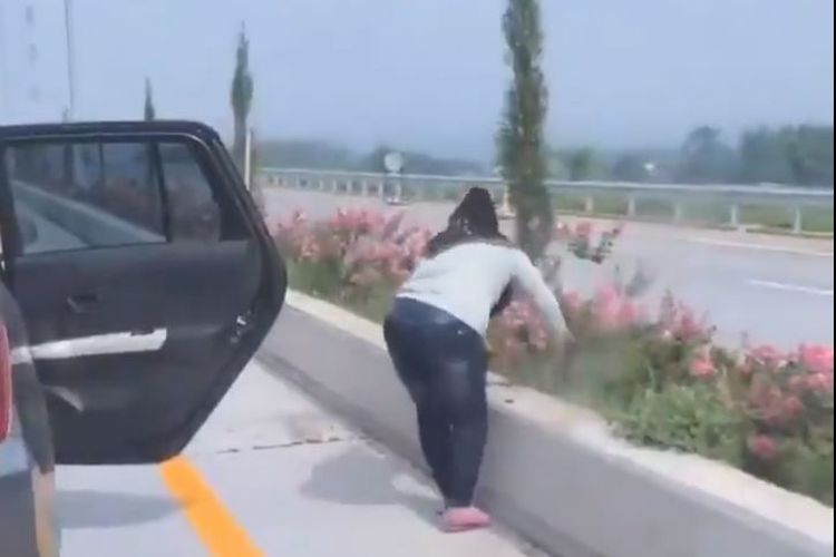 Potongan gambar saat seorang perempuan mencabut tanaman yang ada di pembatas jalan tol.