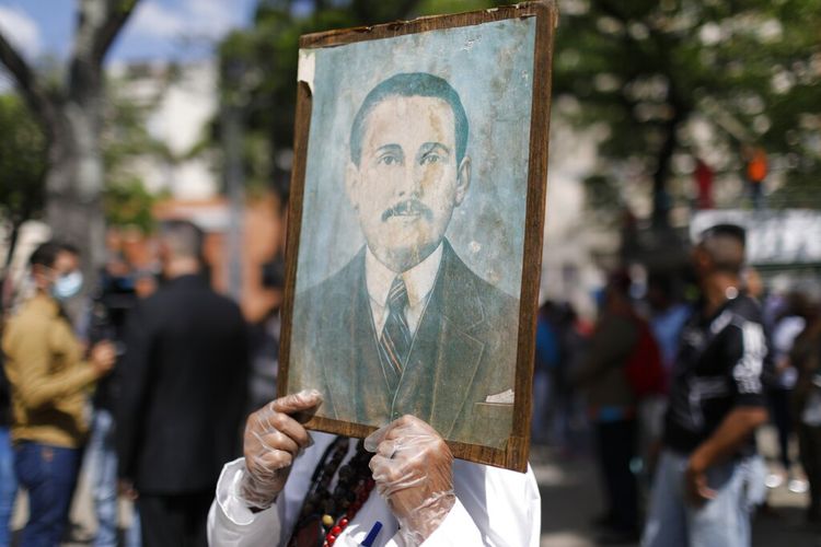 Umat memegang lukisan Venezuela Dr Jose Gregorio Hernandez, yang dibeatifikasi dan dikenal sebagai dokter orang miskin, oleh gereja Katolik, di Caracas, Venezuela, Jumat (30/4/2021). 