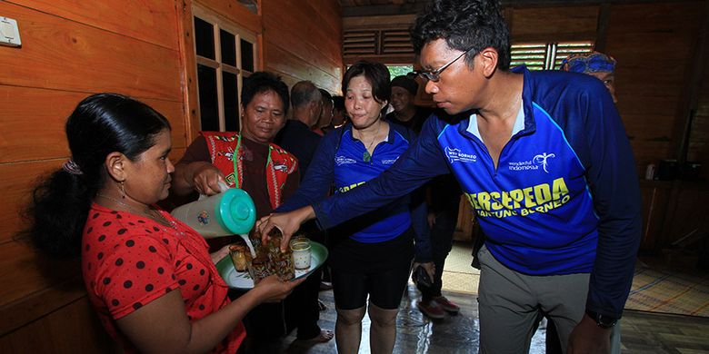 Para peserta Bersepeda di Jantung Borneo saat disuguhi tuak ketika memasuki rumah, Sabtu (28/10/2017).