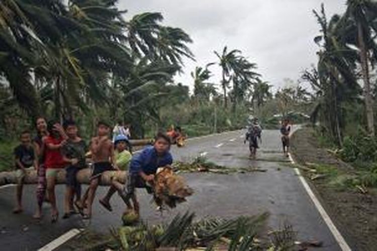 Anak-anak bermain di sebuah pohon yang tumbang akibat terjangan topan Hagupit di dekat kota San Julian, provinsi Samar, Filipina. Sebanyak 27 orang tewas akibat hantaman topan ini sejak Sabtu (6/12/2014).