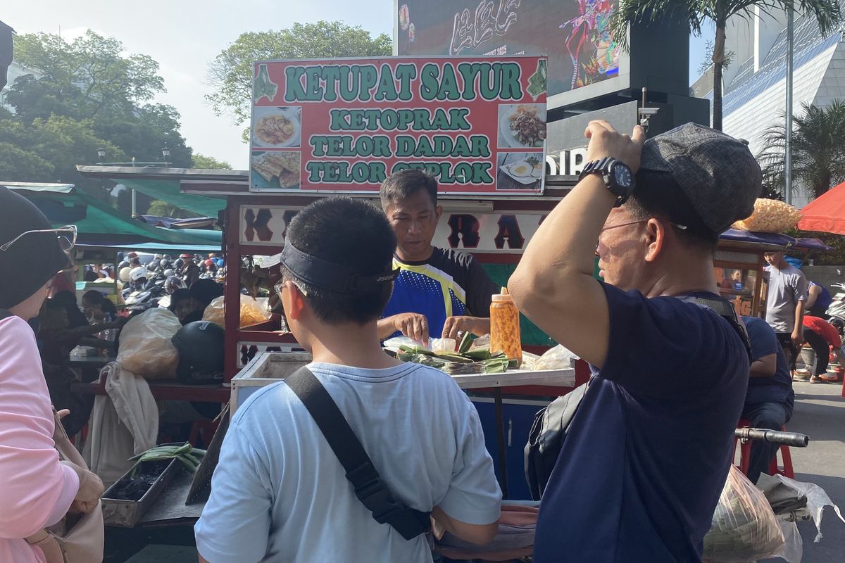 Dodi (50), pedagang otak-otak di CFD Jakarta sedang melayani pembeli, Minggu (11/5/2025).