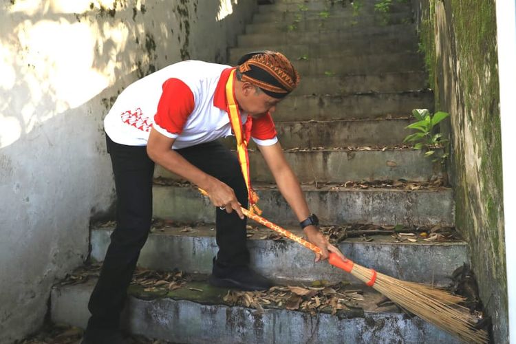 Gubernur Jawa Tengah, Ganjar Pranowo sedang membersihkan tangga di halaman Keraton Surakarta Hadiningrat, Jumat (29/3/2019) pagi.