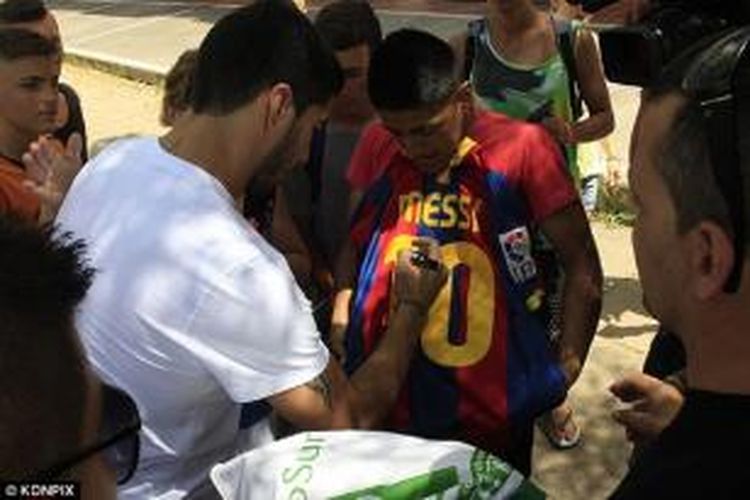 Penyerang Barcelona, Luis Suarez, membubuhkan tanda tangan di atas replika kostum Lionel Messi, milik seorang penggemar, ketika menjalani program latihan individu di Pyrennes, seperti dilansir Daily Mail, Selasa (29/7/2014).
