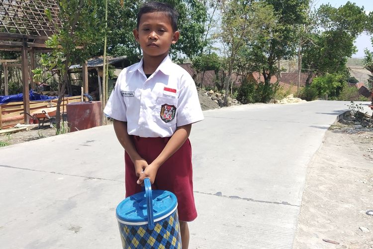 Tegoh Niccolas Saputra (10), siswa kelas 4 SD Negeri 3 Banyurip, Kecamatan Jenar, Sragen, Jawa Tengah membawa termos es untuk dijual di sekolah.
