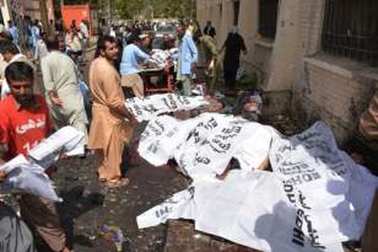 Para sukarelawan menutupi jasad para korban tewas akibat bom di sebuah rumah sakit di Quetta, Pakistan, Senin (8/8/2016).