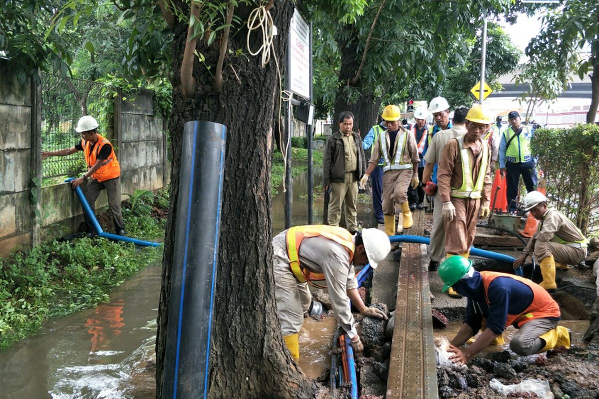 Petugas PT Palyja memperbaiki pipa yang pecah di Jalan Terusan HR Rasuna Said, Selasa (20/2/2018). Akibat pipa pecah, air menggenangi jalan tersebut.