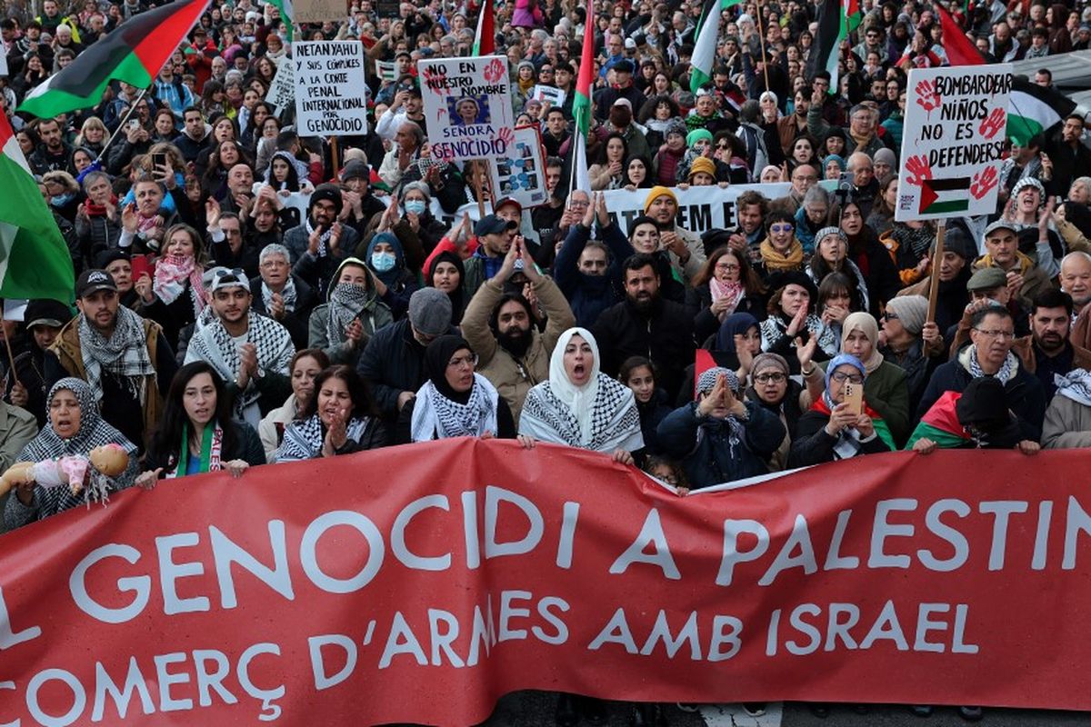Para pengunjuk rasa memegang spanduk bertuliskan 'Hentikan genosida di Palestina dan penjualan senjata dengan Israel' dalam aksi unjuk rasa untuk mendukung warga Gaza, di wilayah Palestina, di Barcelona pada tanggal 20 Januari 2024. Ribuan warga sipil, baik warga Palestina maupun Israel, telah tewas sejak 7 Oktober 2023, setelah militan Hamas Palestina yang berbasis di Jalur Gaza memasuki Israel selatan dan menewaskan 1.200 orang serta menyandera 240 orang, kata Israel, dalam sebuah serangan yang belum pernah terjadi sebelumnya yang memicu perang yang dideklarasikan oleh Israel atas Hamas dengan pemboman balasan di Gaza. 