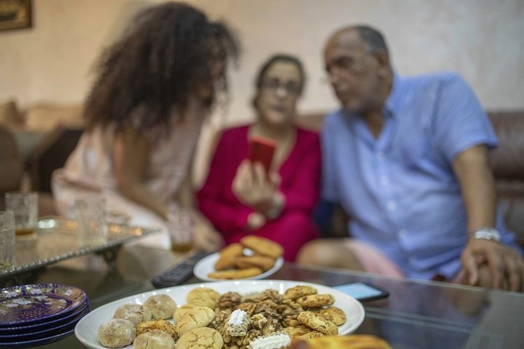 Yousra Sandabad dan orang tuanya, Moustafa dan Afifa, melakukan panggilan video dengan kerabat mereka ketika mereka menikmati permen Maroko pada hari pertama Idul Fitri di tengah lockdown karena pandemi virus corona, di Casablanca, Maroko, Minggu, 24 Mei 2020