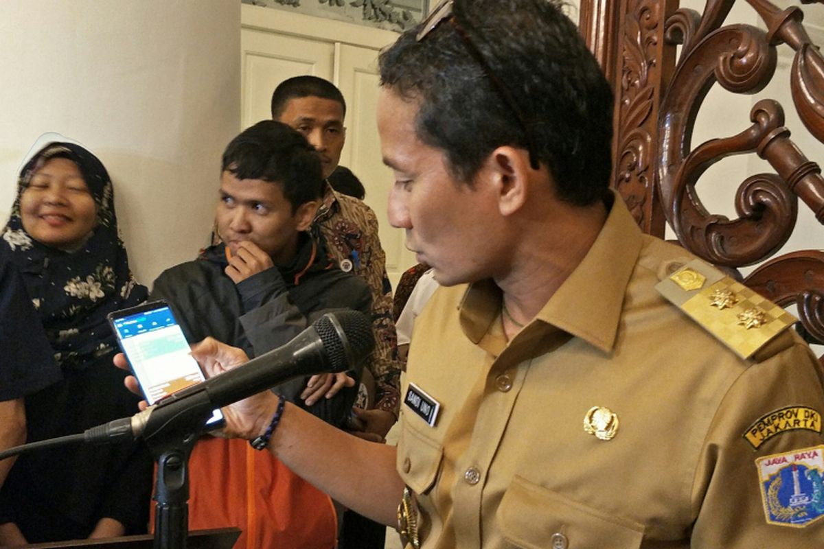 Wakil Gubernur DKI Jakarta Sandiaga Uno menunjukkan aplikasi Pantau Banjir dari ponselnya untuk memantau titik-titik banjir, di Balai Kota DKI Jakarta, Senin (11/12/2017).