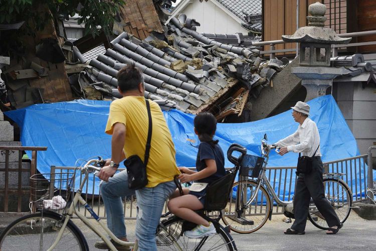 Warga berhenti untuk melihat kerusakan pada sebuah rumah yang hancur akibat gempa bumi di Ibaraki, Utara Osaka, Senin (18/6/2016). 2 orang tewas dan ratusan lainnya terluka akibat gempa berkekuatan 5,3 magnitudo dengan pusat kedalaman 15,4 km.