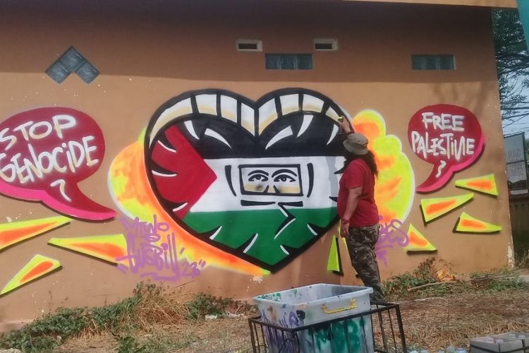 Seniman mural asal Brebes, Gus Bill melakukan protes keras terhadap aksi Israel yang dianggap melakukan genosida terhadap warga Palestina dalam bentuk karya mural di sebuah bangunan di komplek GOR Sasana Adhi Karsa Brebes, Kamis (9/11/2023) (Dok. Pribadi Gus Bill).