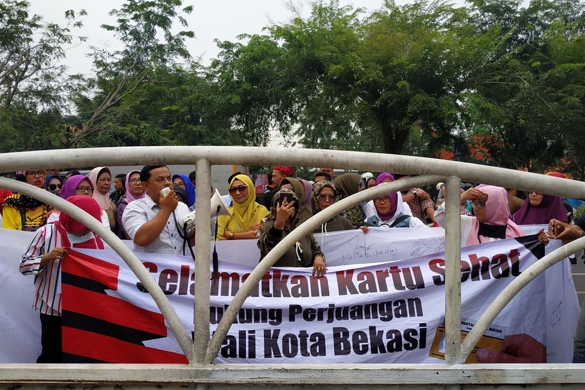 Barisan emak-emak yang mengatasnamakan diri sebagai Pejuang Kartu Sehat Kota Bekasi mendemo DPRD Kota Bekasi, Senin (16/12/2019).