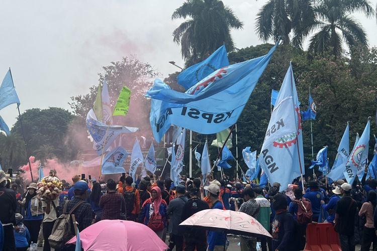 Massa Buruh Nyalakan Flare dan Kibarkan Bendera Saat Aksi May Day di Monas, Rabu (1/5/2024).