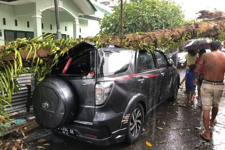 Sebuah mobil yangs ednag parkir di pinggir jalan rusak akibat tertimpa pohon tumbang di kawasan Batu Gajah, Kecamatan Sirimau, Ambon, Kamis (2/1/2020)