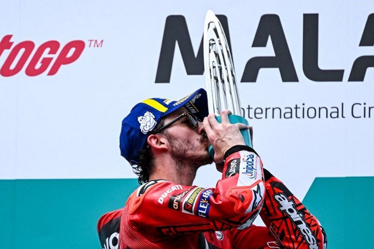 Francesco Bagnaia mencium trofi setelah meraih kemenangan di MotoGP Malaysia 2022 di Sirkuit Sepang, Minggu (23/10/2022). (Foto oleh MOHD RASFAN/AFP)