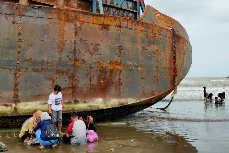 Pengunjung Objek Wisata PAI Kota Tegal, Jawa Tengah saat berada di dekat sebuah kapal tongkang yang terdampar, Rabu (20/1/2021)