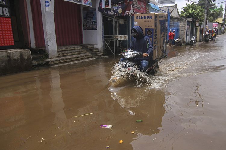 Pengendara melintasi genangan banjir di Kampung Utan, Citayem, Depok, Jawa Barat, Senin (8/2/2021). Banjir setinggi 30 cm - 50 cm tersebut disebabkan karena meluapnya aliran kali dan hujan deras yang mengguyur Kota Depok.