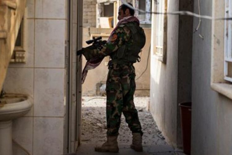 Seorang anggota pasukan Peshmerga sedang memeriksa bangunan di Bashiqa, Irak.  
