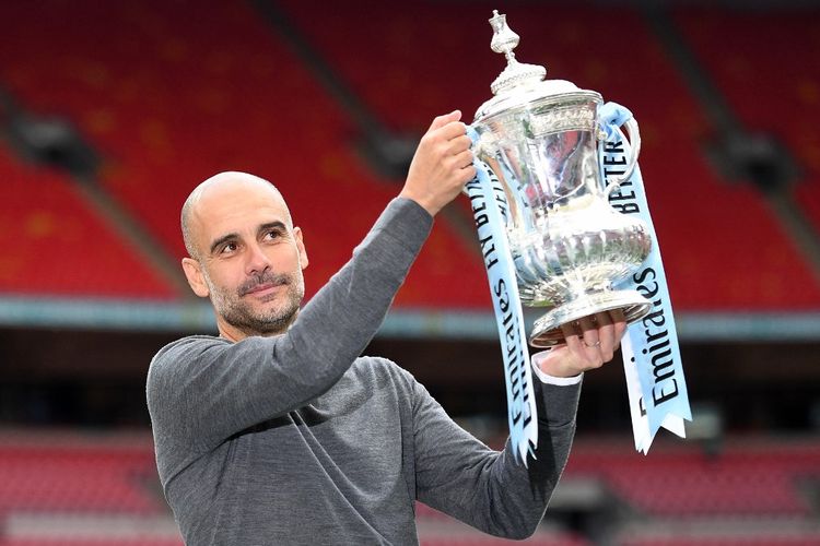 Manajer Manchester City, Pep Guardiola, mengangkat Piala FA usai laga final Man City Vs Watford di Stadion Wembley, London, Inggris, Sabtu (18/5/2019).