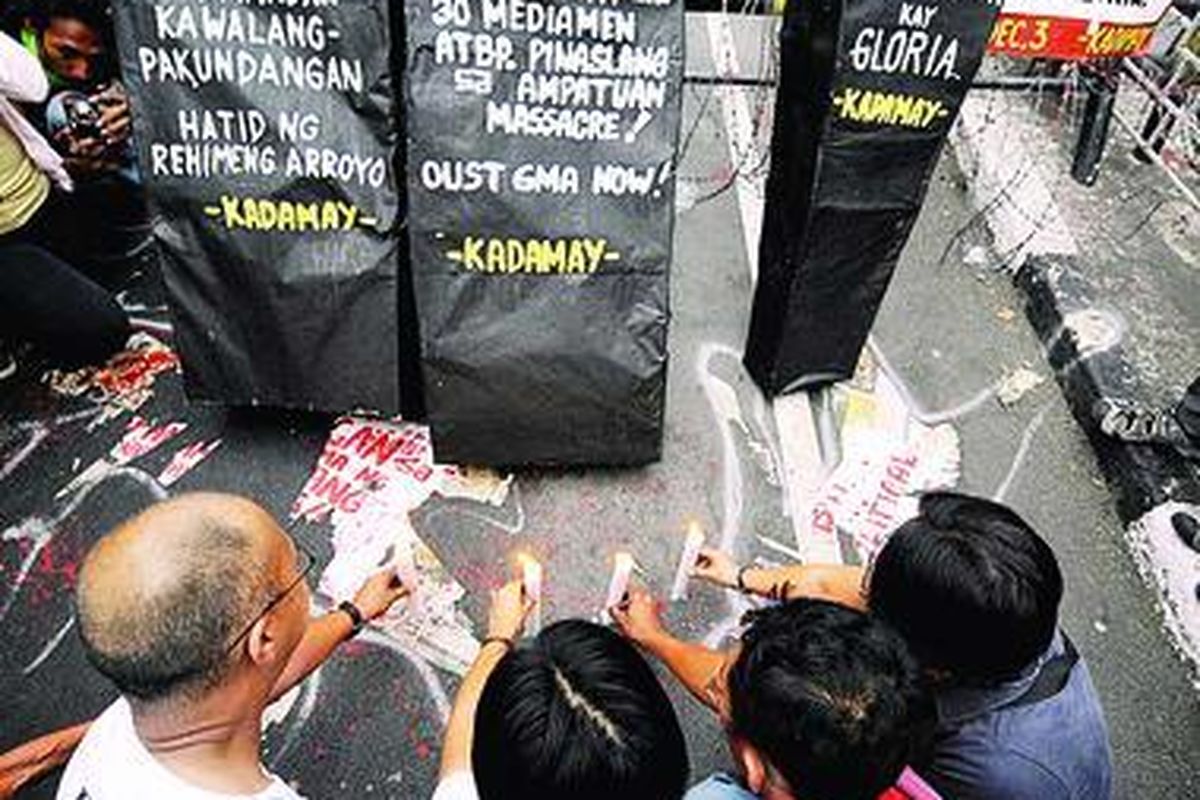 Para aktivis di Manila, Filipina, Kamis (3/12), menyalakan lilin di depan jenazah buatan yang menggambarkan korban pembantaian di Filipina selatan.