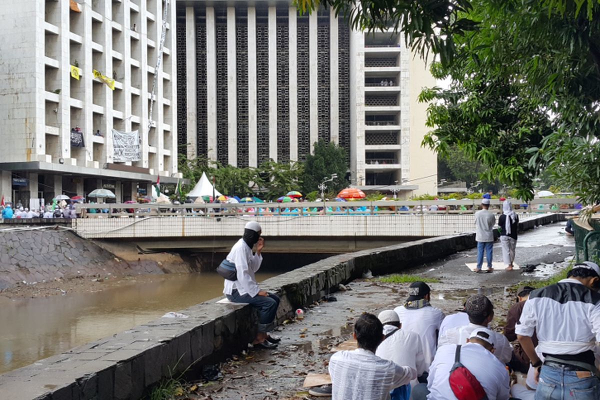 Massa aksi demonstrasi pada Jumat (31/3/2017) atau disebut aksi 313 mendengarkan khotbah yang disampaikan khotib di Masjid Istiqlal, Jakarta Pusat, di bawah hujan yang mengguyur kawasan tersebut.