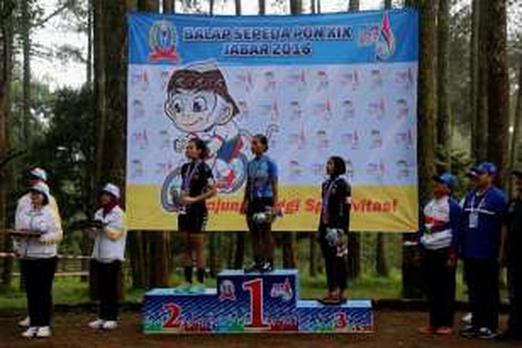 Peraih medali emas balap sepeda cross country putri PON XIX Jawa Barat 2016, Kusmawati Yazid (tengah), bediri di atas podium setelah penyerahan medali. Pebalap sepeda Riau, Wilhemina (kiri) dan Novianan (kanan), finis di urutan pertama dan kedua. Balap sepeda cross country putri berlangsung di Cikole, Lembang, Senin (19/9/2016).