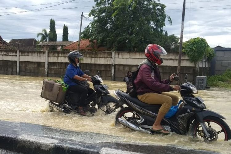 Pengendara sepeda motor melintasi Jalur Pantura Tegal-Pemalang yang tergenang akibat hujan dan luapan sungai, Kamis (14/1/2021) (Istimewa)