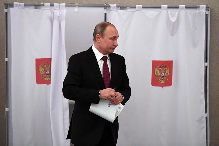Presiden Vladimir Putin keluar dari bilik suara usai memberikan pilihannya dalam pemilihan presiden Rusia di Moskwa, Minggu (18/3/2018).