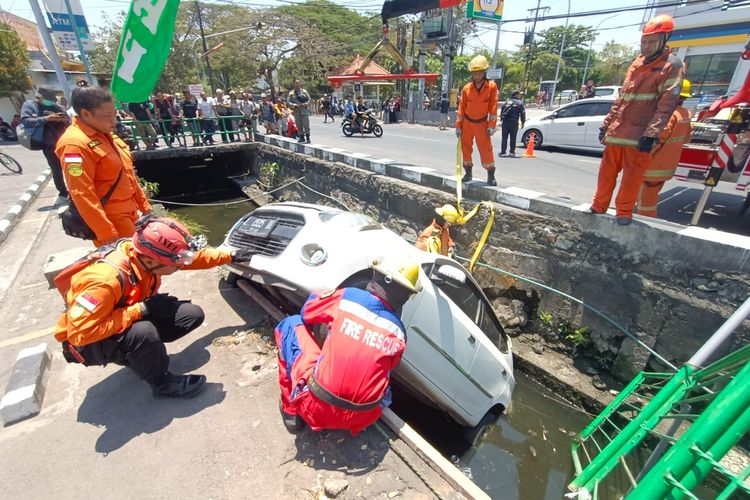 Petugas saat evakuasi mobil masuk sungai di Surabaya