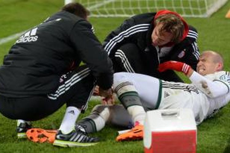 Tim medis membantu gelandang Bayern Muenchen, Arjen Robben, yang mengalami cedera saat membawa timnya mengalahkan Augsburg 2-0 di babak ketiga DFB Pokal, Rabu (4/12/2013). Bayern ke perempat final.