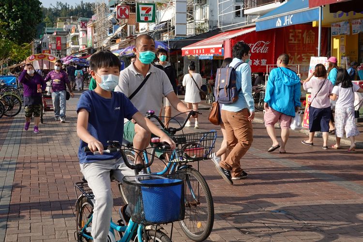 Warga Hong Kong terlihat memakai masker bepergian di pulau Cheung Chau saat libur Paskah, di tengah merebaknya virus corona. Foto diambil pada 12 April 2020.