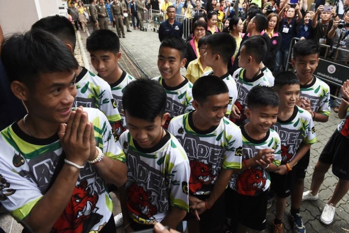 12 remaja laki-laki dan pelatih sepak bola mereka, Ekkapol Chantawong (kiri), tiba untuk konferensi pers di Chiang Rai pada 18 Juli 2018, setelah keluarnya mereka dari rumah sakit. Mereka mengungkapkan kisah terjebak di dalam goa Tham Luang, Thailand.