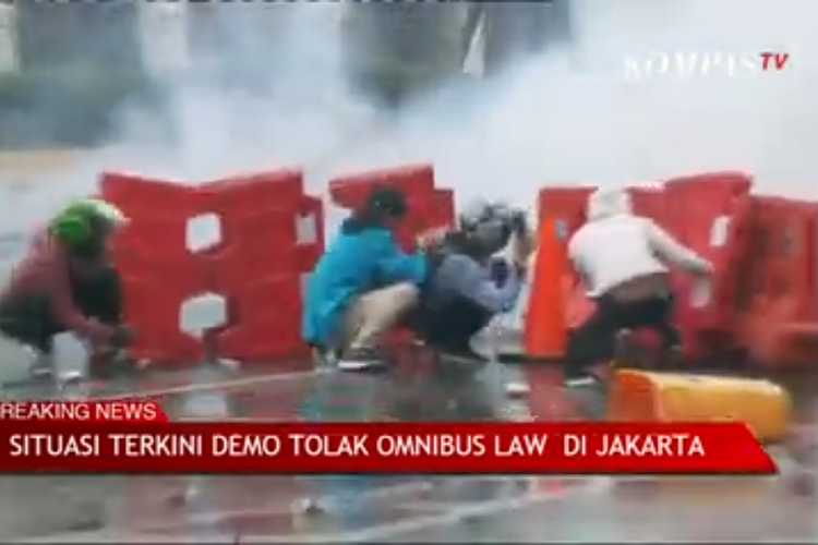 Massa berlindung dibalik separator sambil melempar polisi dengan batu di kawasan Harmoni, Jakarta Pusat
