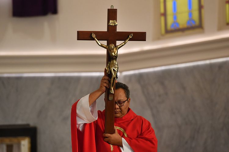 Seorang romo mengangkat salib saat Ibadah Jumat Agung di Gereja Katedral Surabaya, Jawa Timur, Jumat (10/4/2020). Ibadah untuk mengenang sengsara dan wafatnya Yesus tersebut disiarkan secara langsung melalui dalam jaringan agar umat Katolik melakukan ibadah dari rumahnya masing-masing guna mencegah penyebaran Virus Corona (COVID-19).