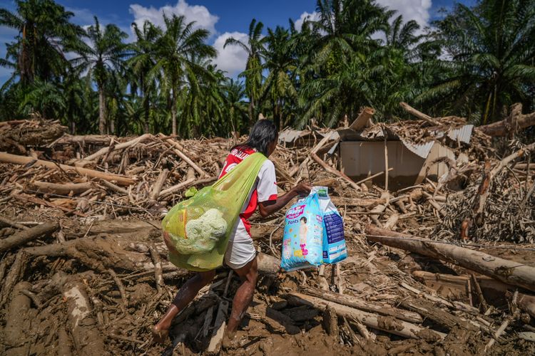 Warga melintasi jalan akses antardesa pascabanjir bandang di Desa Tanjung Karang, Karang Baru, Kabupaten Aceh Tamiang, Aceh, Minggu (7/12/2025). Akses penghubung Desa Tanjung Karang dan Desa Menang Gini yang sempat tertutup tumpukan kayu gelondongan akhirnya bisa terbuka usai pemerintah mengerahkan alat berat untuk pembersihan sehingga mobilitas masyarakat, termasuk distribusi bantuan menjadi bisa dilakukan. 