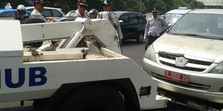 Sebuah mobil Toyota Innova berpelat merah diderek petugas dari Dinas Perhubungan dalam penertiban parkir liar di Jalan Gajah Mada, tepatnya di depan PN Jakarta Pusat, Selasa (9/9/2014).