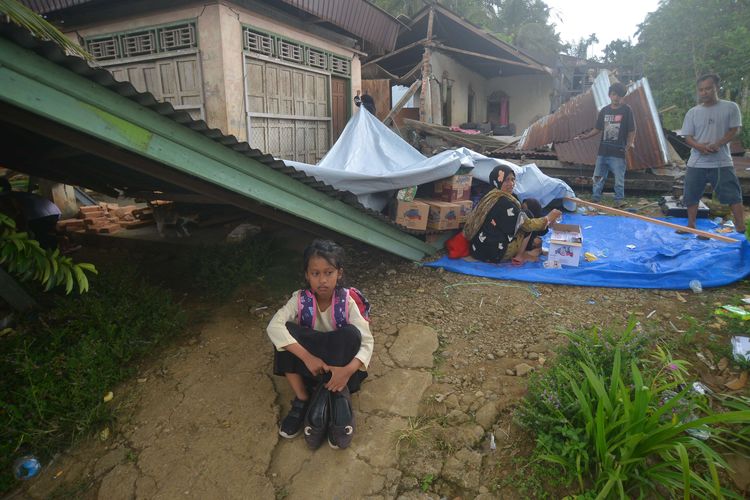 Warga duduk di halaman rumahnya yang rusak akibat gempa di Jorong Pinagar, Nagari Aua Kuning, Kabupaten Pasaman Barat, Sumatera Barat, Jumat (25/2/2022). Badan Nasional Penanggulangan Bencana (BNPB) menyatakan gempa berkekuatan magnitudo 6,2 di Pasaman Barat dan sekitarnya itu mengakibatkan tujuh warga meninggal dunia.