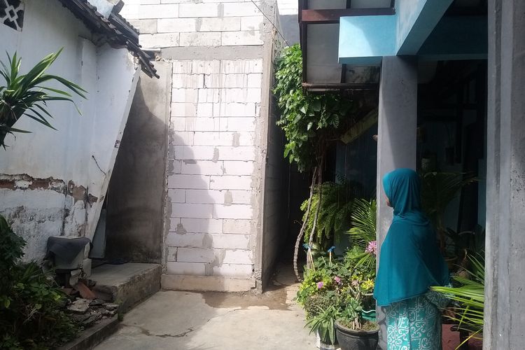 TATAP—Seorang warga menatap tembok yang menutup jalan akses warga RT 01/RW 07, Kelurahan Bangunsari, Kecamatan Ponorogo, Kabupaten Ponorogo, Jawa Timur, Senin (3/7/2023) siang. 