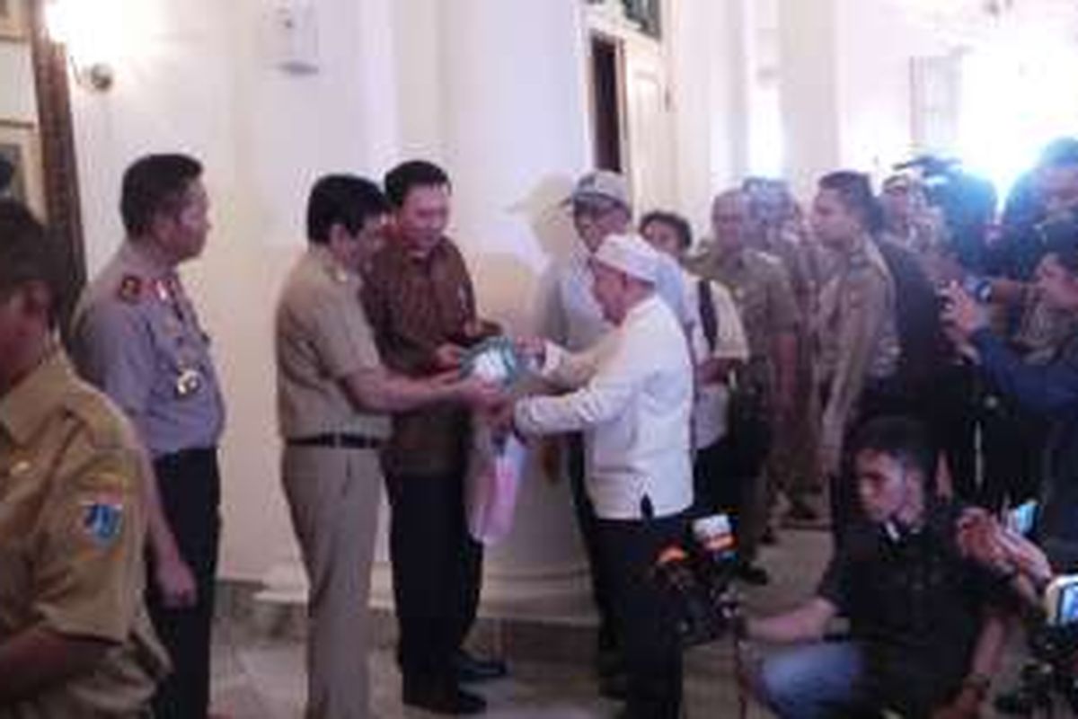 Gubernur DKI Jakarta Basuki Tjahaja Purnama terlihat diberikan Al-Qur'an oleh seorang warga saat halalbihalal, di Balai Kota DKI Jakarta, Senin (11/7/2016).