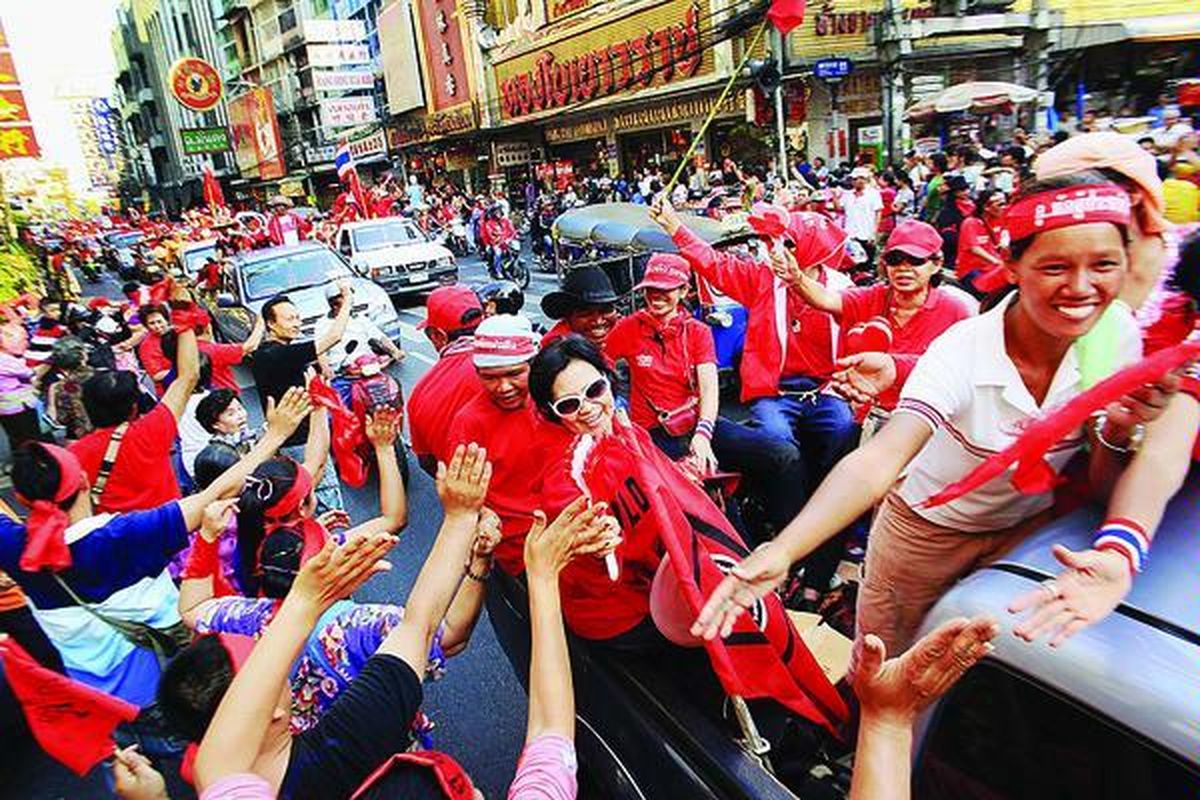 Warga  menyemangati para demonstran pendukung mantan Perdana Menteri Thaksin Shinawatra di Bangkok, Thailand, Sabtu (20/3). Pasukan kaus merah itu berarakan ke seantero Bangkok untuk menarik dukungan dan simpati warga.