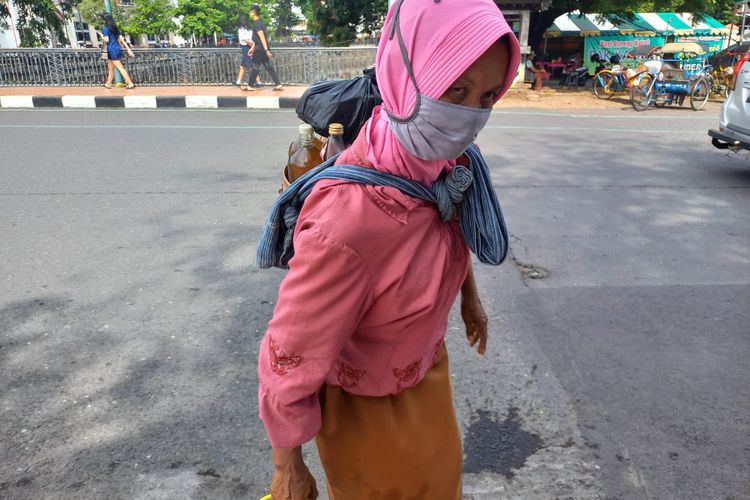 Sri Mulyani menggendong jamu tradisional hasil olahannya di Kawasan Kota Lama Semarang, Selasa (14/6/2022).